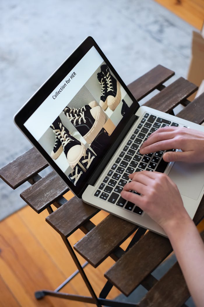Hands browsing sneakers on laptop, showcasing online store shopping experience.